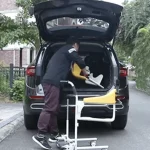 Person Putting Transfer Commode and Over Toilet Wheelchair inside Car Trunk