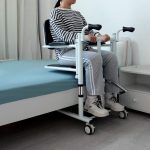 Adjustable Patient Lift Near Bed and Person Sitting on It