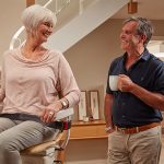 Old Woman Sitting on Infinity Stair Lift a Curved Stair Lift and Talking With a Man