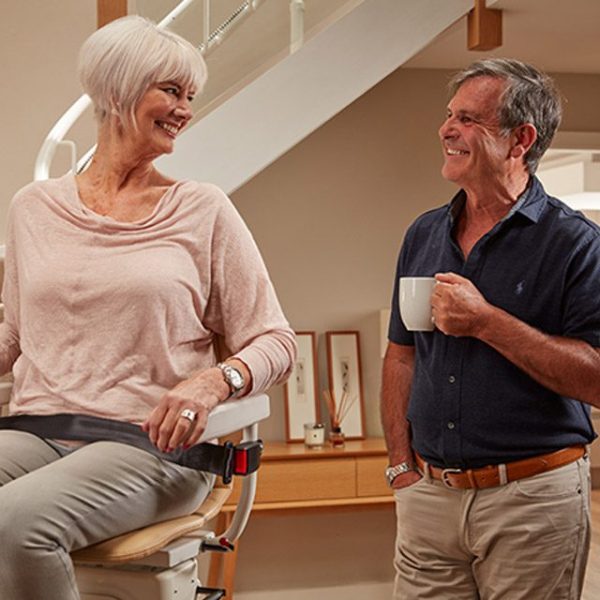Old Woman Sitting on Infinity Stair Lift a Curved Stair Lift and Talking With a Man Old Woman Sitting on Infinity Stair Lift a Curved Stair Lift and Talking With a Man