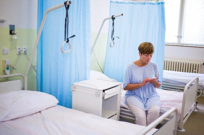 Senior on medical bed using phone (1)