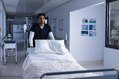 male-doctor-walking-with-bed-hospital-corridor